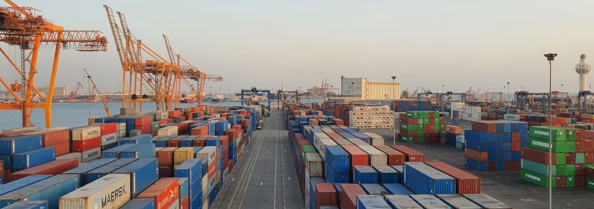 Shipping containers stacked at a port, representing tariffs and import costs